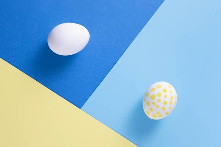 Two white eggs on blue and yellow paper