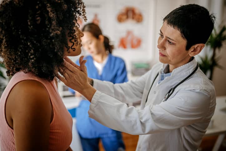 Doctor checking a woman's thyroid