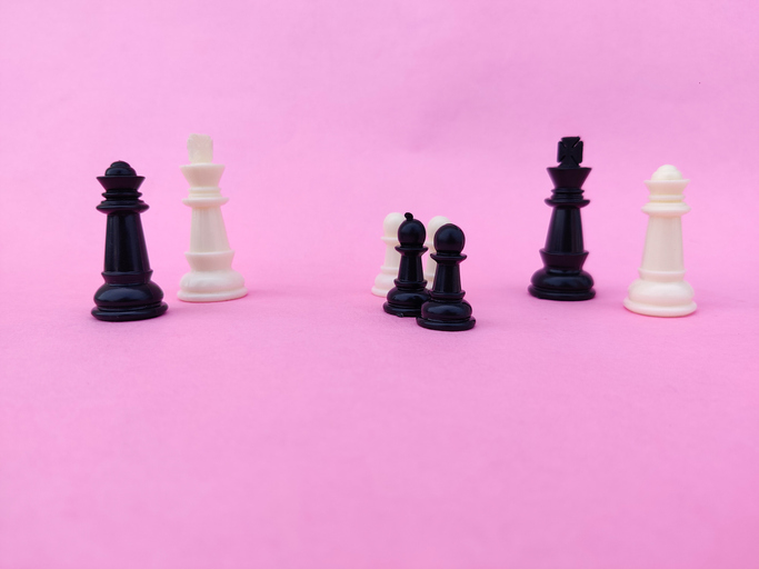 Black and white chess pieces isolated on pink background.