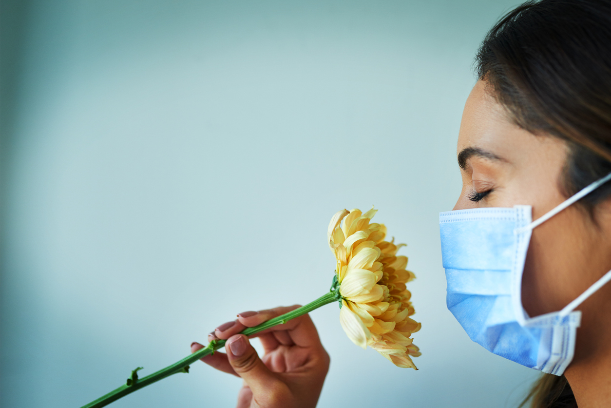 woman-in-surgical-mask-smelling-flower