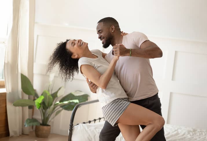 Man and woman dancing and smiling in bedroom 