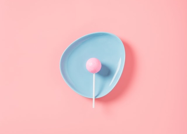 pink lollipop on a blue plate on a pink background