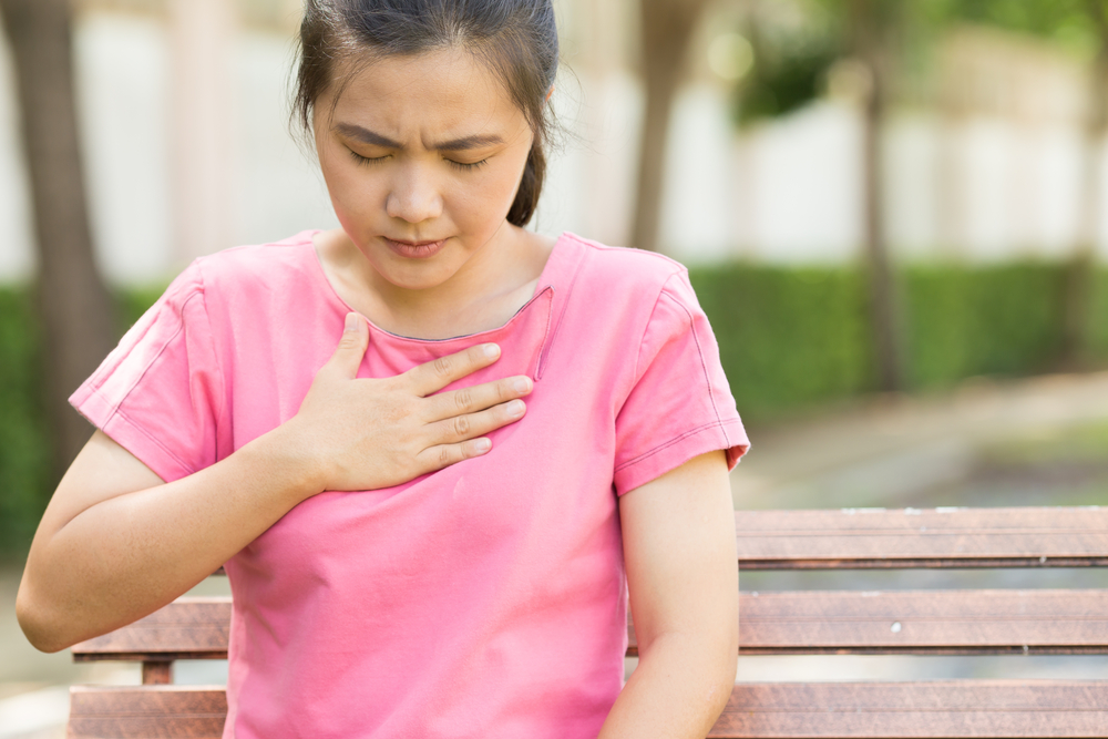 Woman in pink t-shirt with case of heartburn