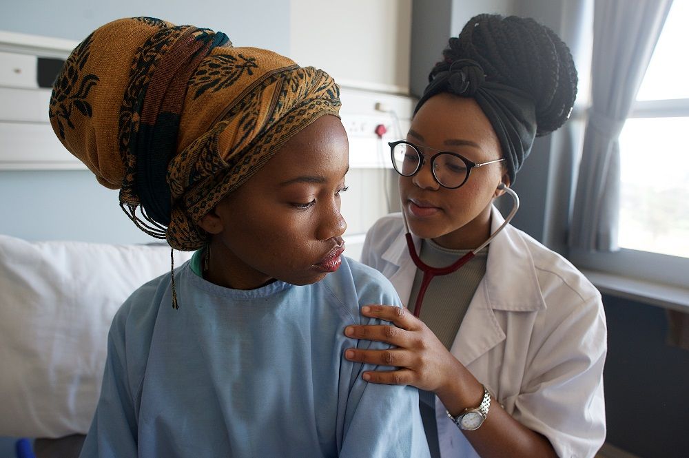 Young Female Doctor listening with stethoscope on patient's back 