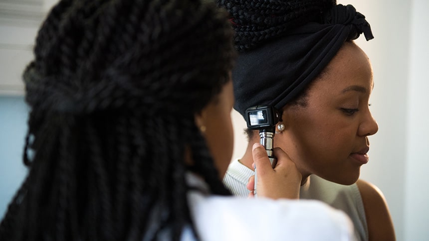 Female doctor examining woman's ear with otoscope stock photo- stockstudioX