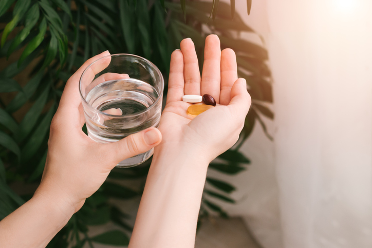 Woman holding pills and a glass of water