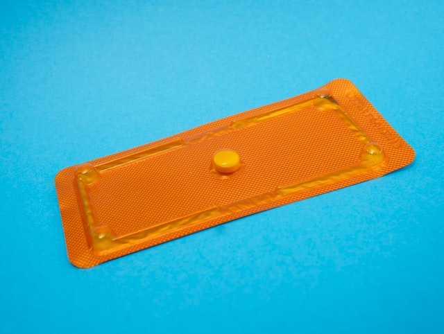Morning after pill in orange packet on blue background