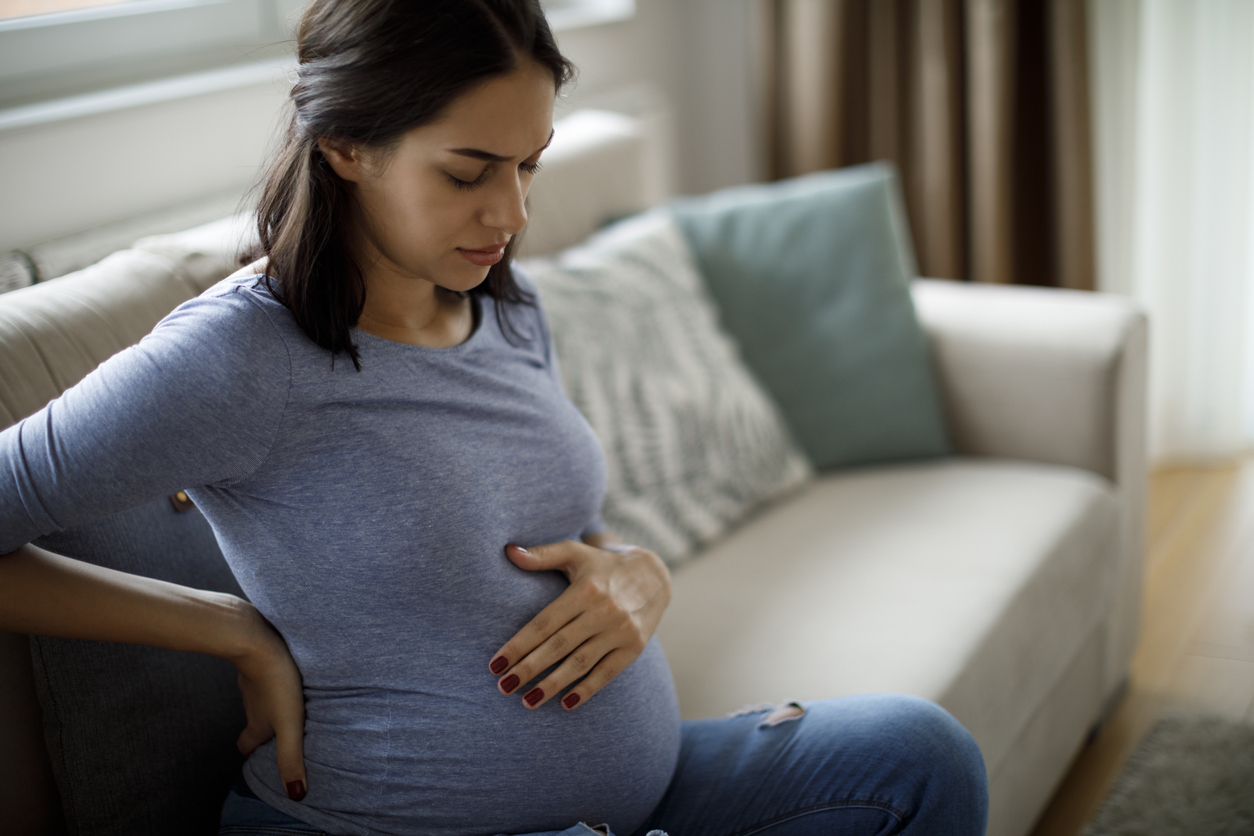 Pregnant woman sitting on a couch with backache