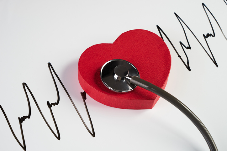 Medical stethoscope and red heart with cardiogram on white background