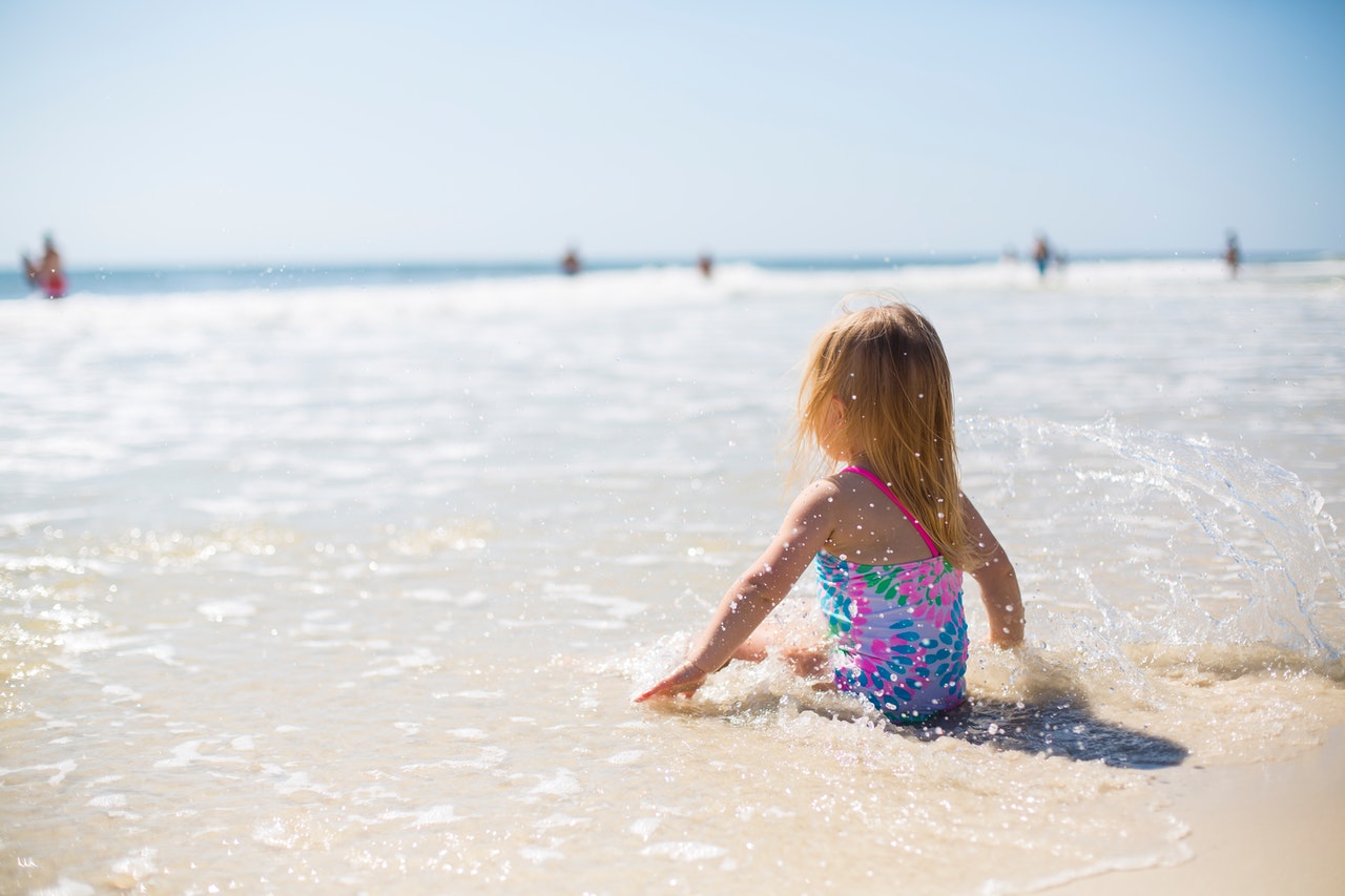 Young baby girl sitting on a sandy beach wearing swimming costume (Credit Ashley K Little)