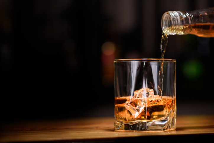 Whiskey being poured into a glass with ice