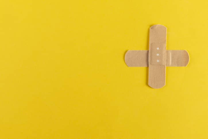 Two adhesive bandaids in a cross on a yellow background