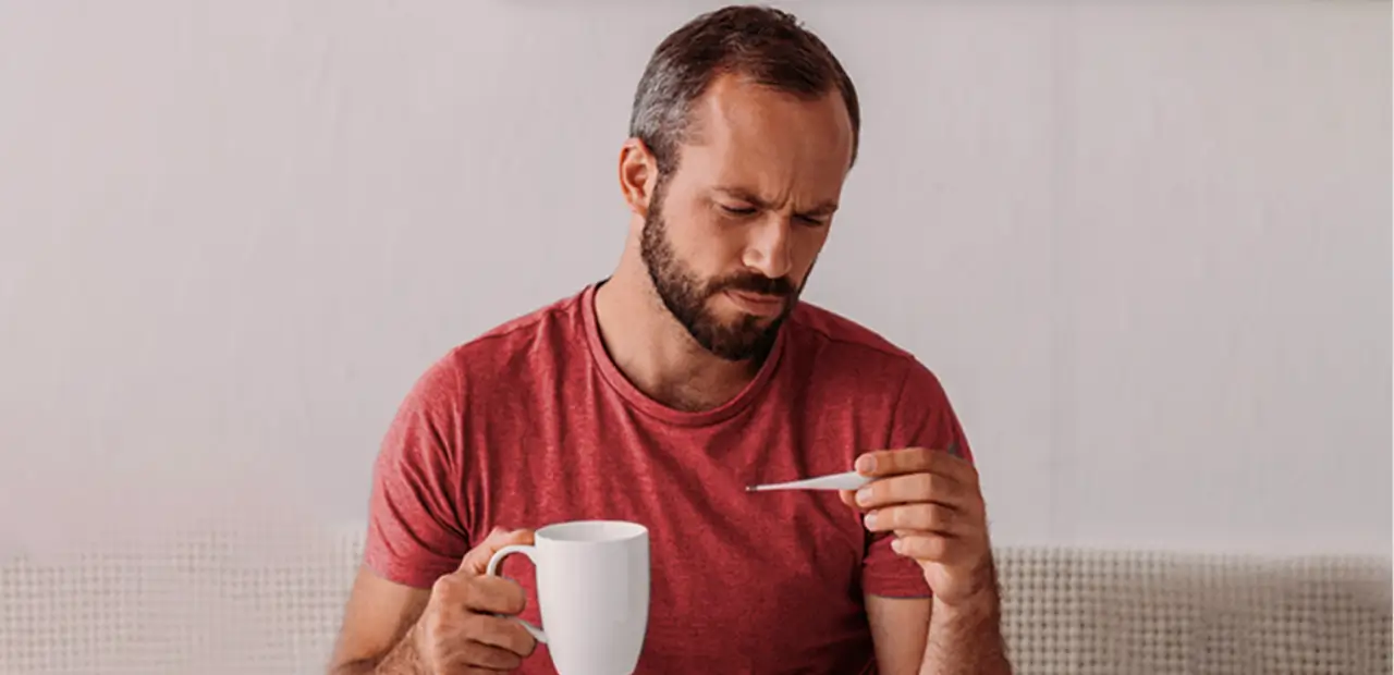 Hombre mirando un termómetro mientras toma su café