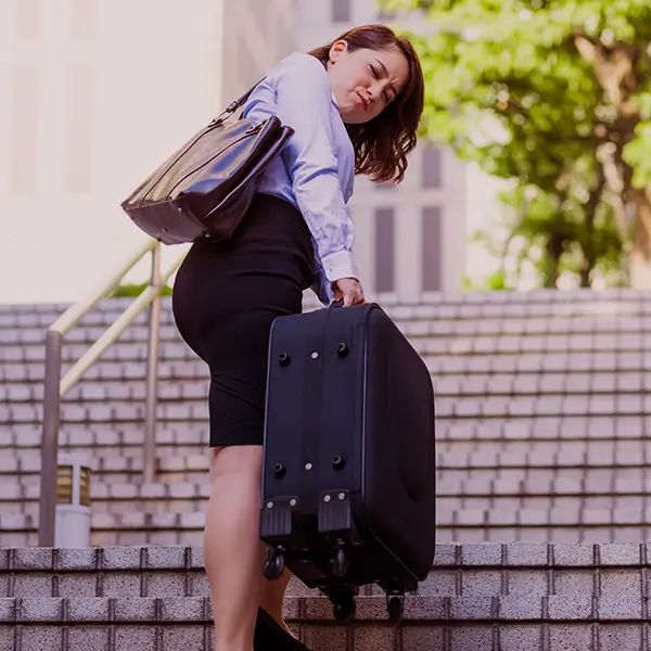 Mujer levantando maleta pesada por las escaleras