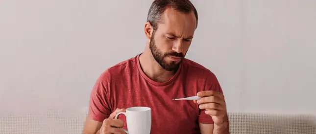 Hombre mirando un termómetro mientras toma su cafe