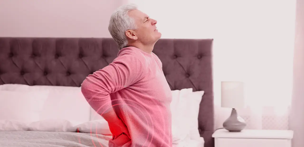 Hombre de edad levantandose de la cama con dolor espalda