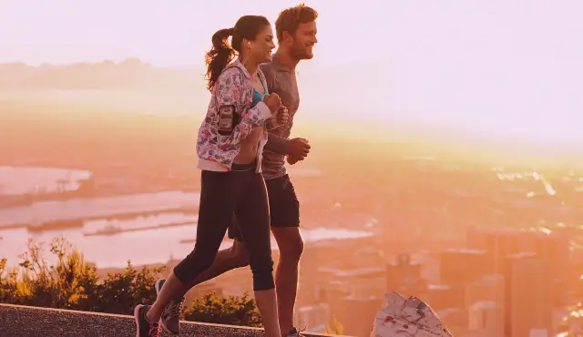 Dos jovenes corriendo al amanecer con vista a la ciudad