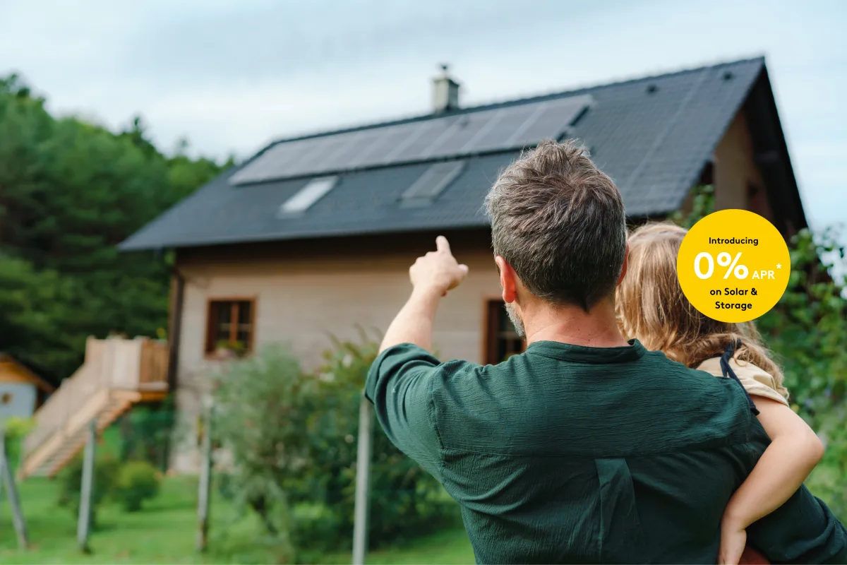 Father and child pointing and looking at solar panels on roof with 0% financing banner overlay