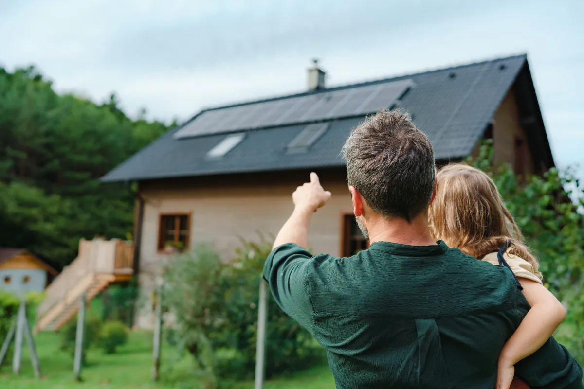 Father and child pointing and looking at solar panels on roof with 0% financing banner overlay
