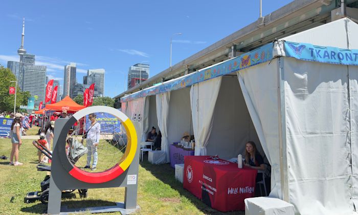 Kiosque au marché Tkaronto, dans le cadre du FIFA Fan Festival™ de Toronto, avec une roue médicinale au premier plan et la Tour CN en arrière-plan