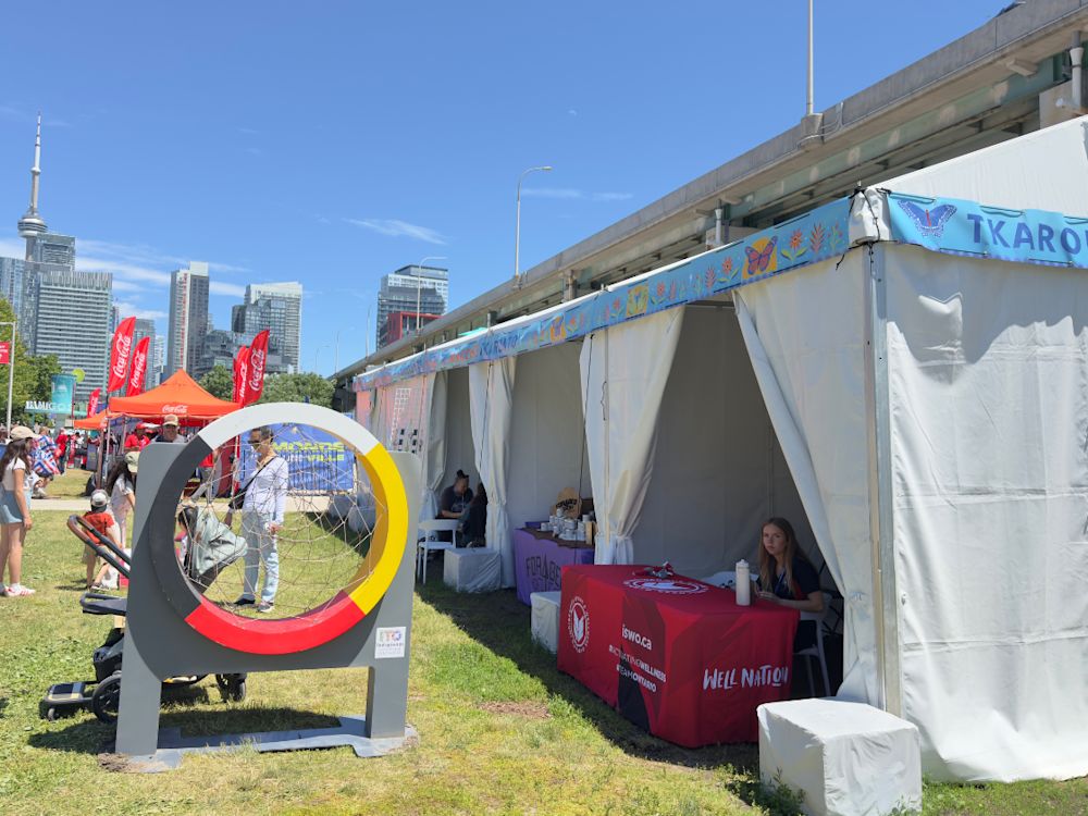 Booth at Tkaronto Market at the FIFA Fan Festival™ Toronto, with a medicine wheel in the forefront and CN Tower in the background