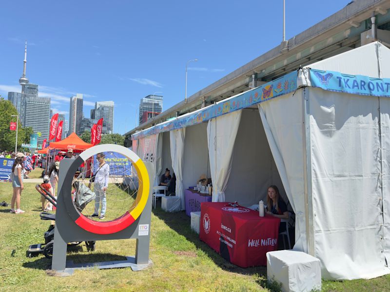 Booth at Tkaronto Market at the FIFA Fan Festival™ Toronto, with a medicine wheel in the forefront and CN Tower in the background