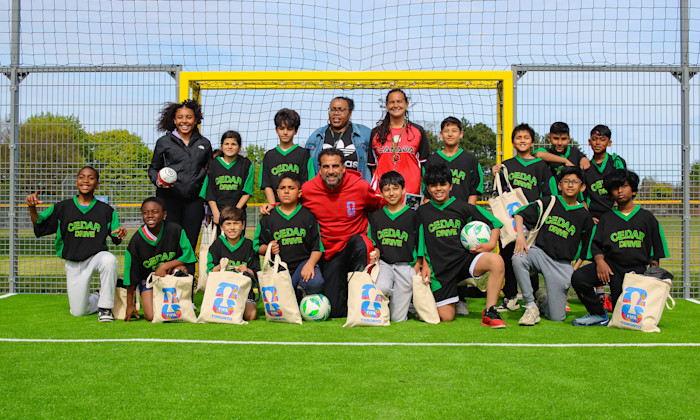 A Soccer team posing for a photo on the pitch near the net.