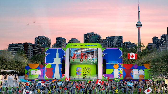 An artist's rendering of a large stage at FIFA Fan Festival Toronto with a large screen showing a soccer game above performers on stage. A crowd stands in front of the stage with the Toronto skyline and CN Tower in the background.