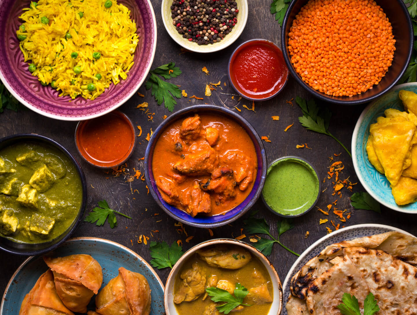 Close up of a vibrant spread of Indian cuisine with bowls of paneer, rice & butter chicken on a table