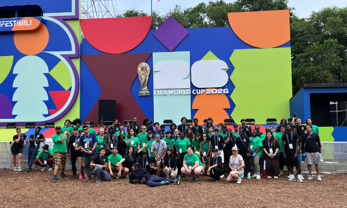 FIFA workers together in front of a large FIFA World Cup 2026 sign
