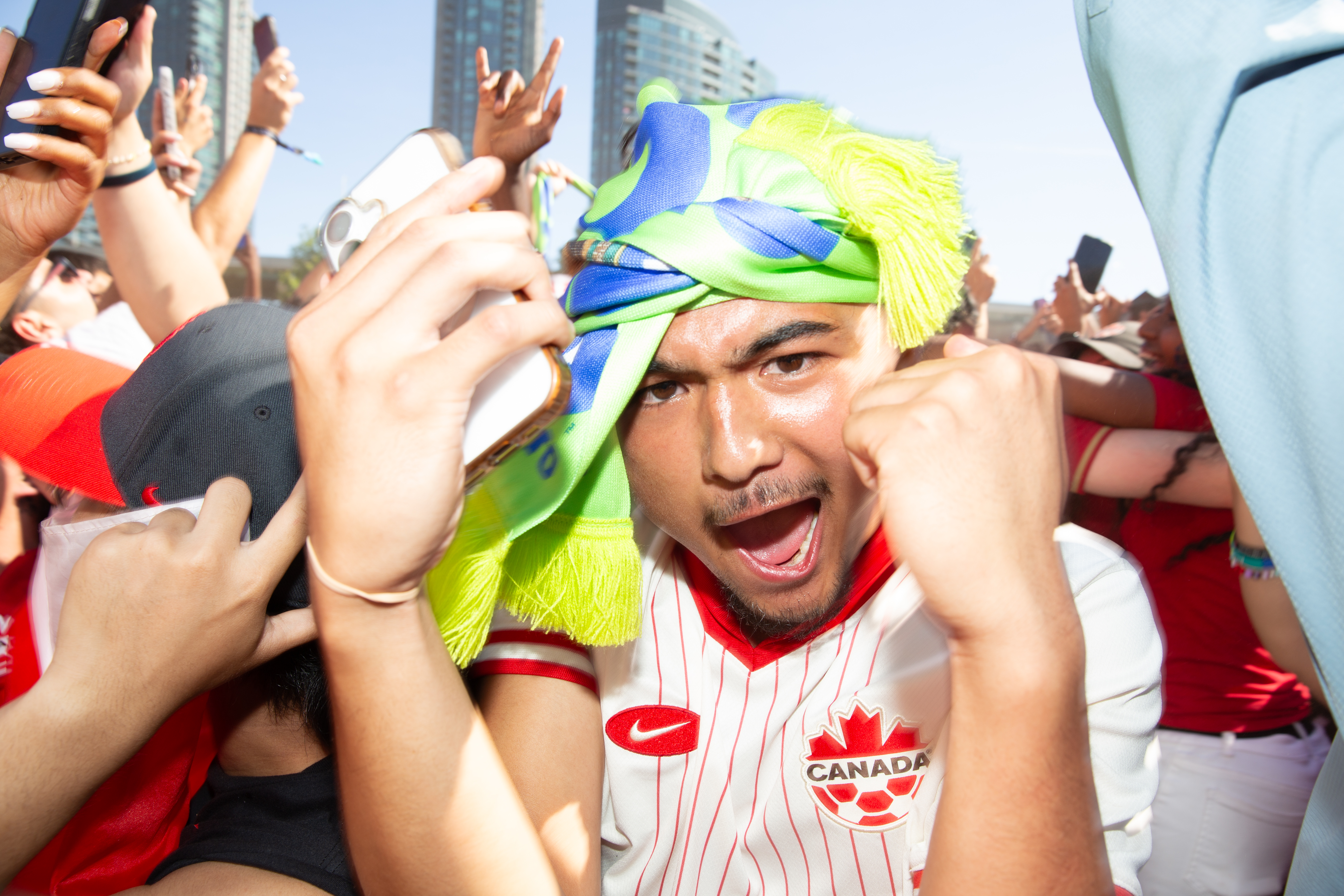 A person wearing a FIFA World Cup™ Toronto branded scarf on his head as they cheer with fans