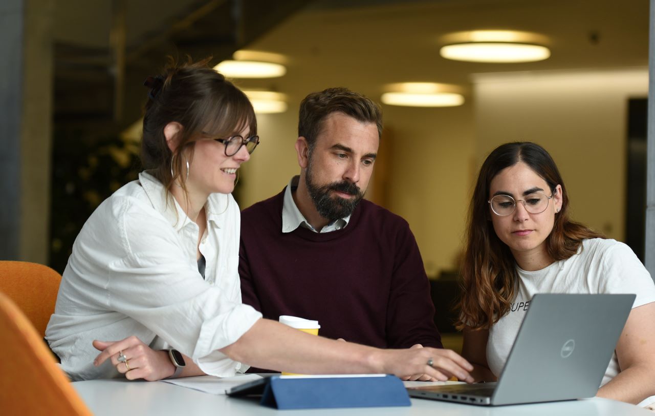 a group of instructors gathering around a laptop