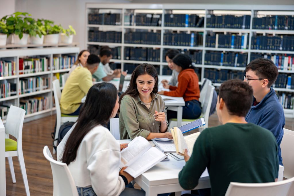 students sitting in a library with a librarian.