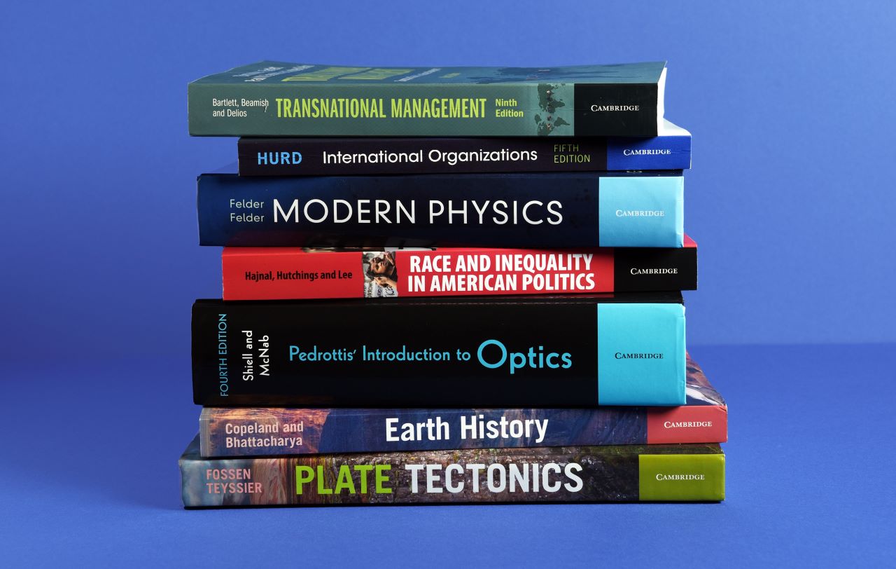 a stack of higher education textbooks against a blue background