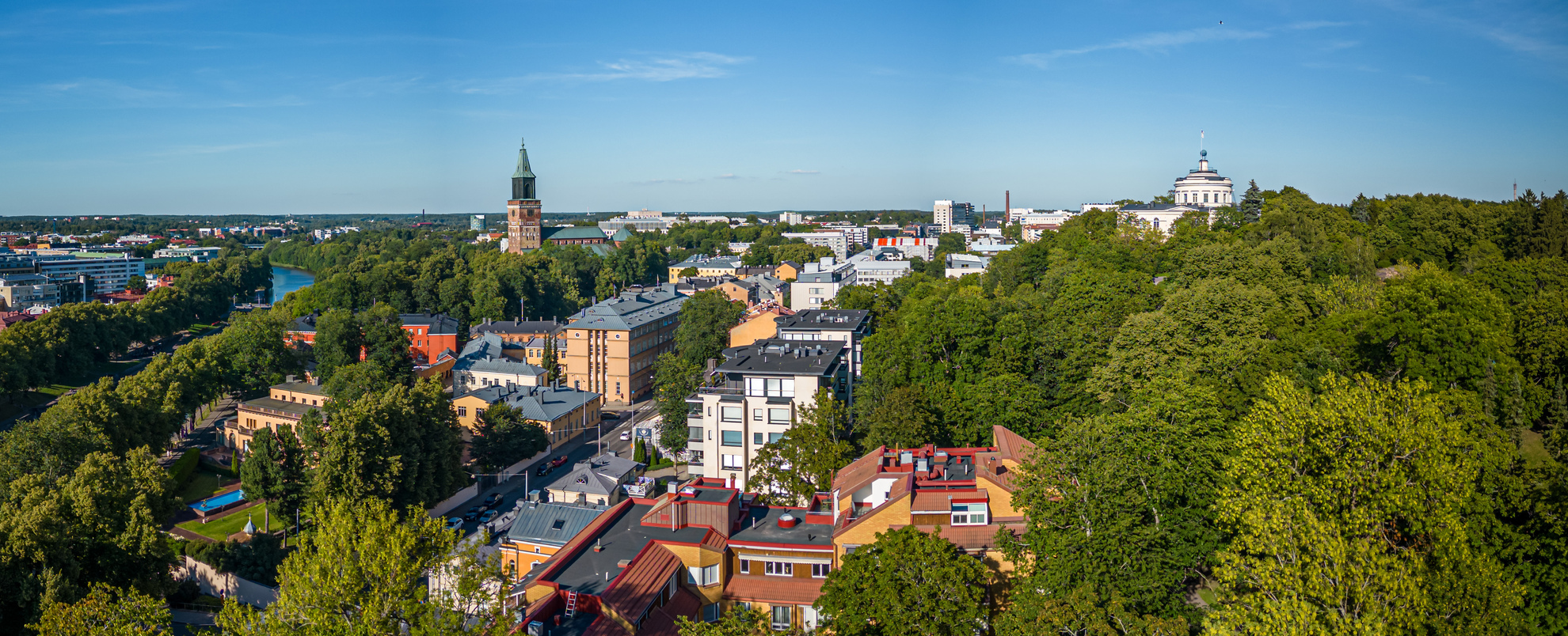 A stock image of a sustainable city. The cityscape features modern buildings, green parks, and trees.