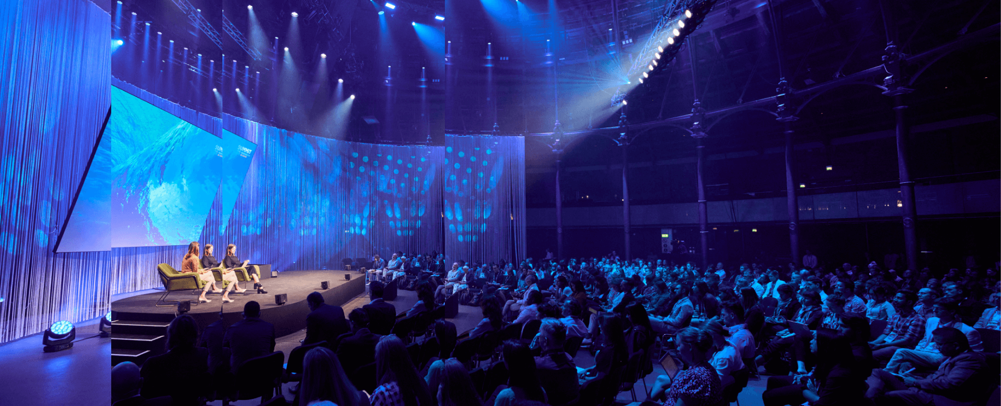 People talking on a stage in front of a large audience