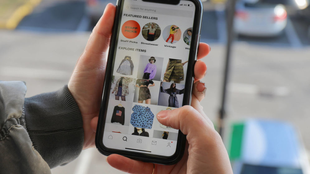 Person holding mobile phone scrolling through fashion items