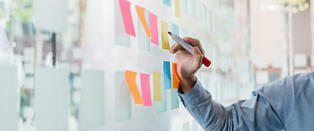 Person drawing on acrylic board with post it notes