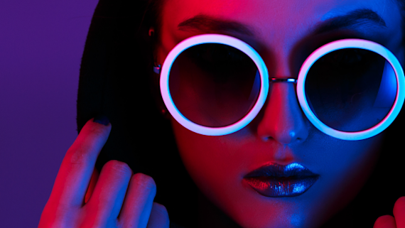 Purple background with a woman in a hood and circular glasses