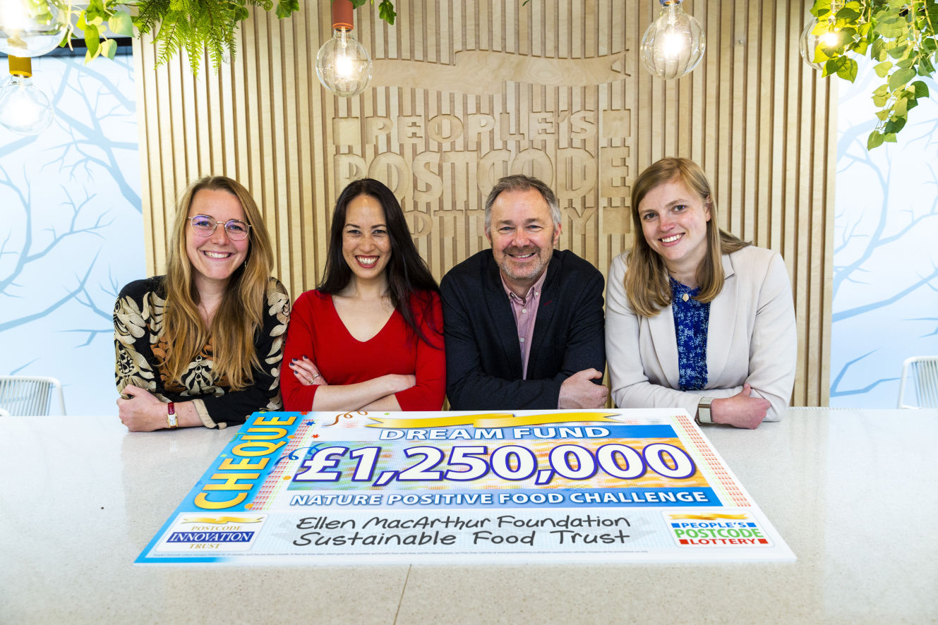 Four people sat behind a large cheque