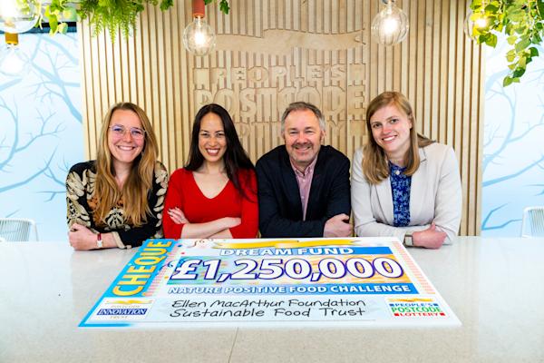 Four people sat behind a large cheque