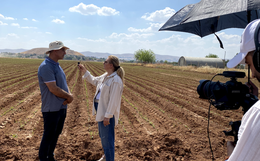 A woman interviewing a man in a field