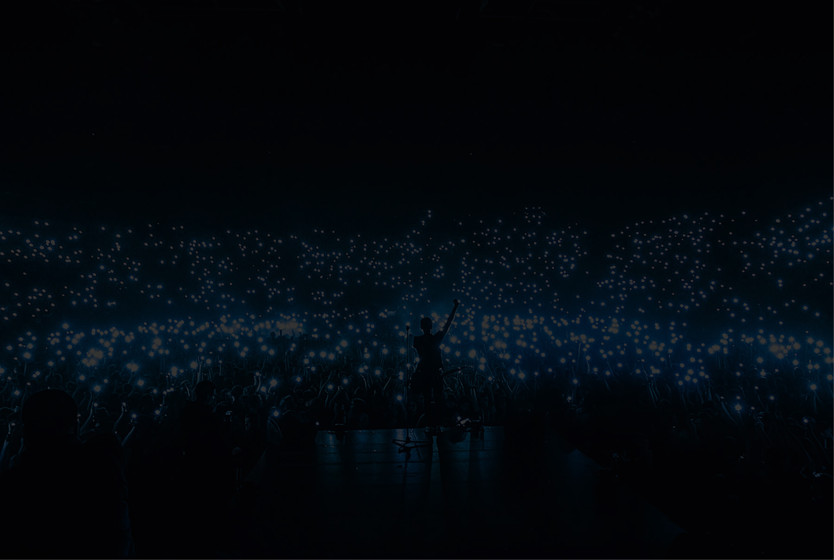 Mobile phone lights in the night sky at a concert