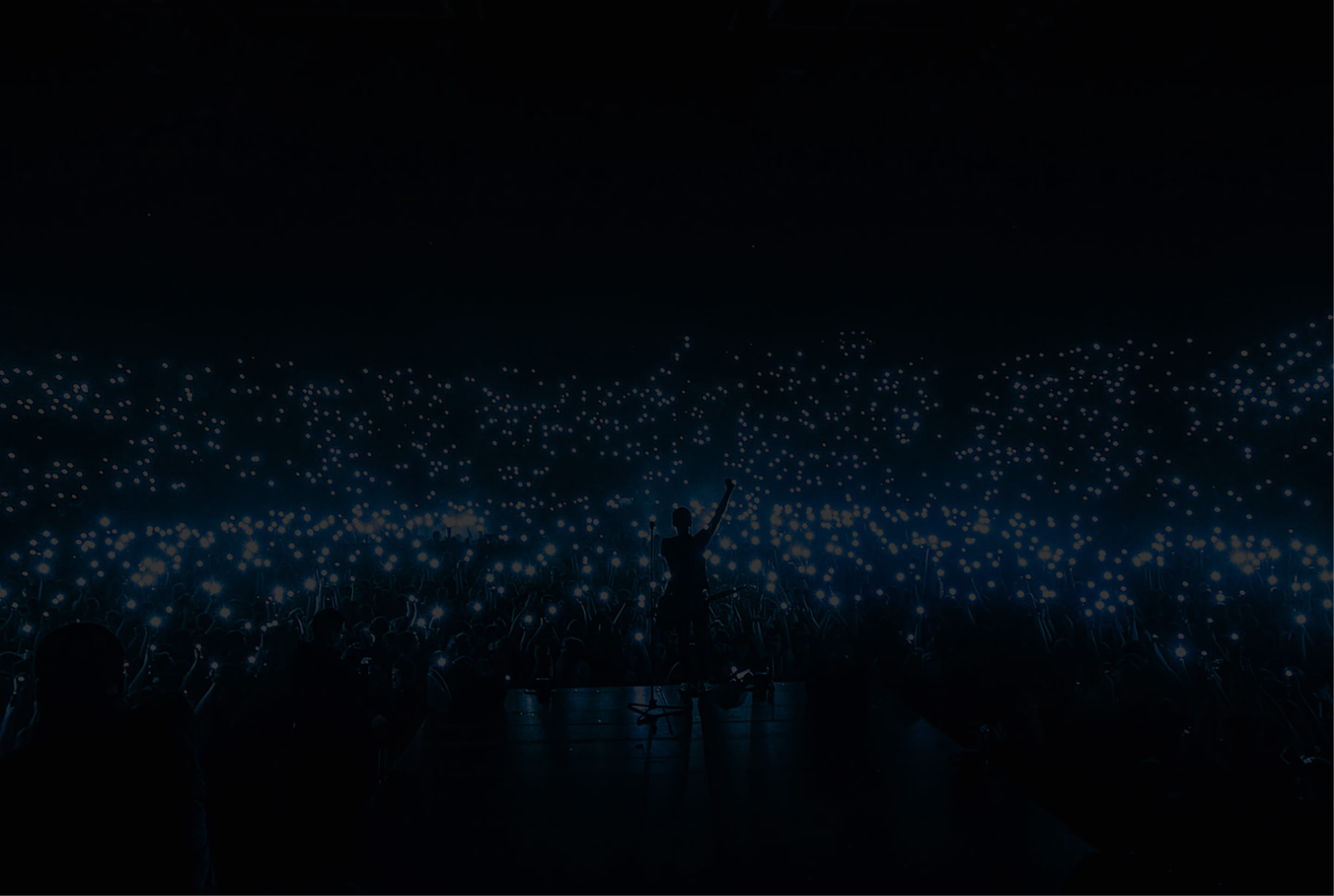 Mobile phone lights in the night sky at a concert