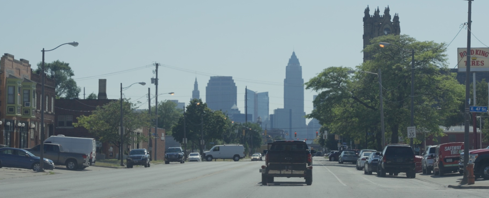 A landscape image of Cleveland with skyscrapers, trees, cars and houses. 