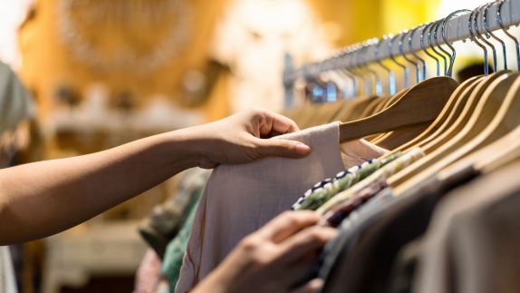 person selecting clothes from clothes rail