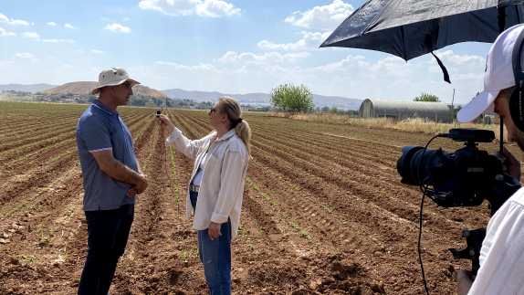 A women interviewing a man in a field