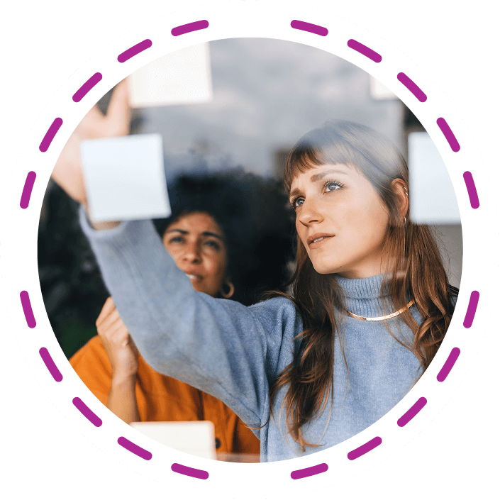 Two women putting ideas onto postit notes