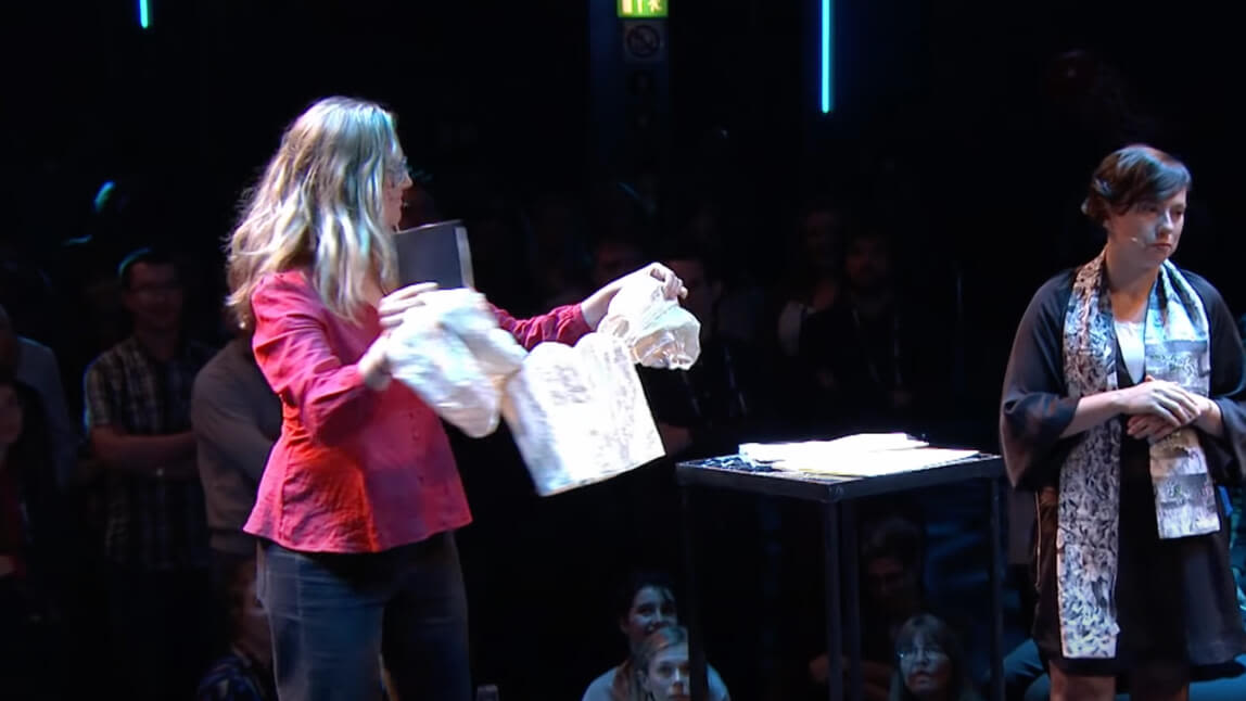 person holding a t-shirt while talking on stage