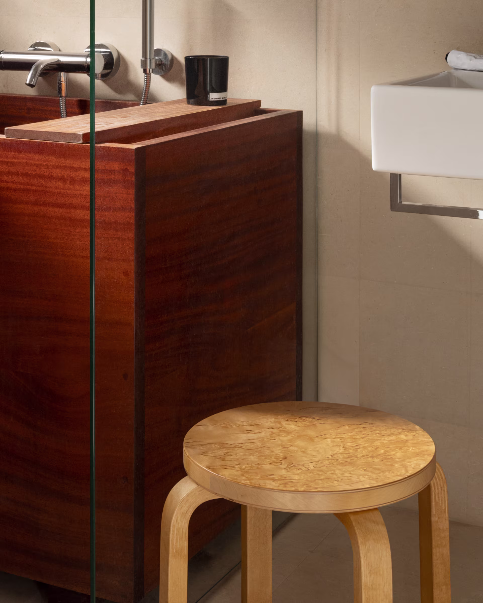 Bathroom with the Cury Birch stool by Artek for Nordiska Galleriet next to a dark wood bathtub.